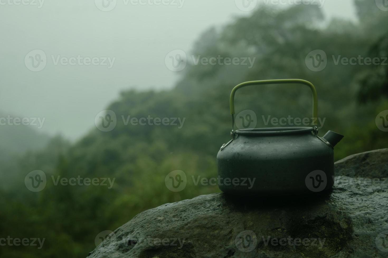 tea pot on top of stone in the mountain with fog background photo