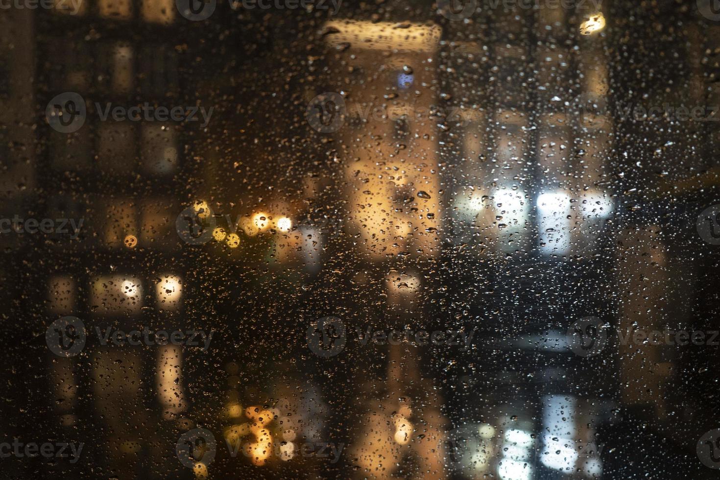 Rain drops on glass window at night photo