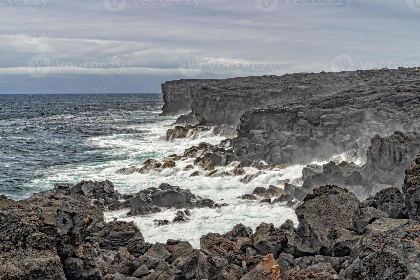 sea in tempest breaking waves on lava rock cliff photo