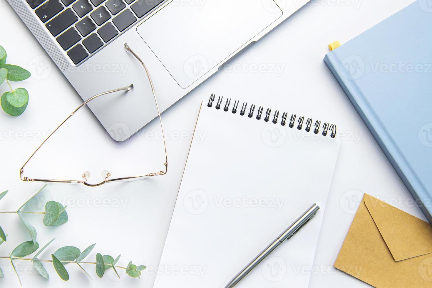 Modern white office desk table with laptop, notebook and other supplies. photo