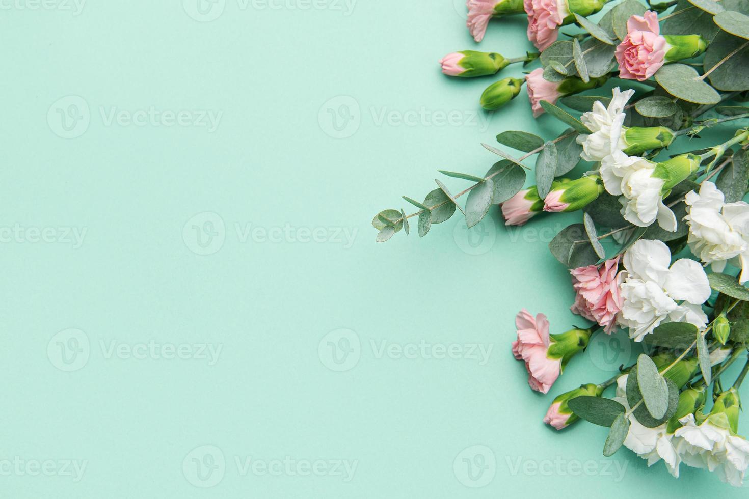 A bouquet of white and pink carnations with eucalyptus branches on a soft green background. photo