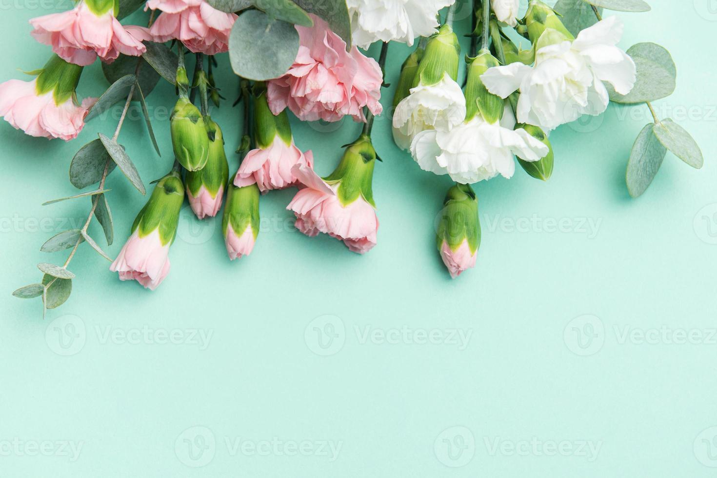 A bouquet of white and pink carnations with eucalyptus branches on a soft green background. photo