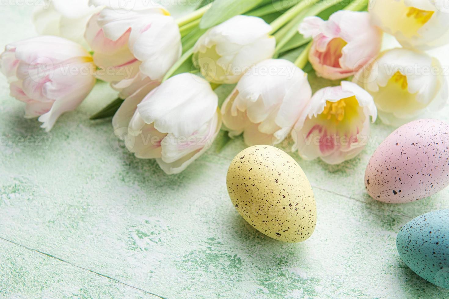 Pascua de Resurrección huevos pintado pastel colores y rosado tulipanes en un verde de madera antecedentes. foto
