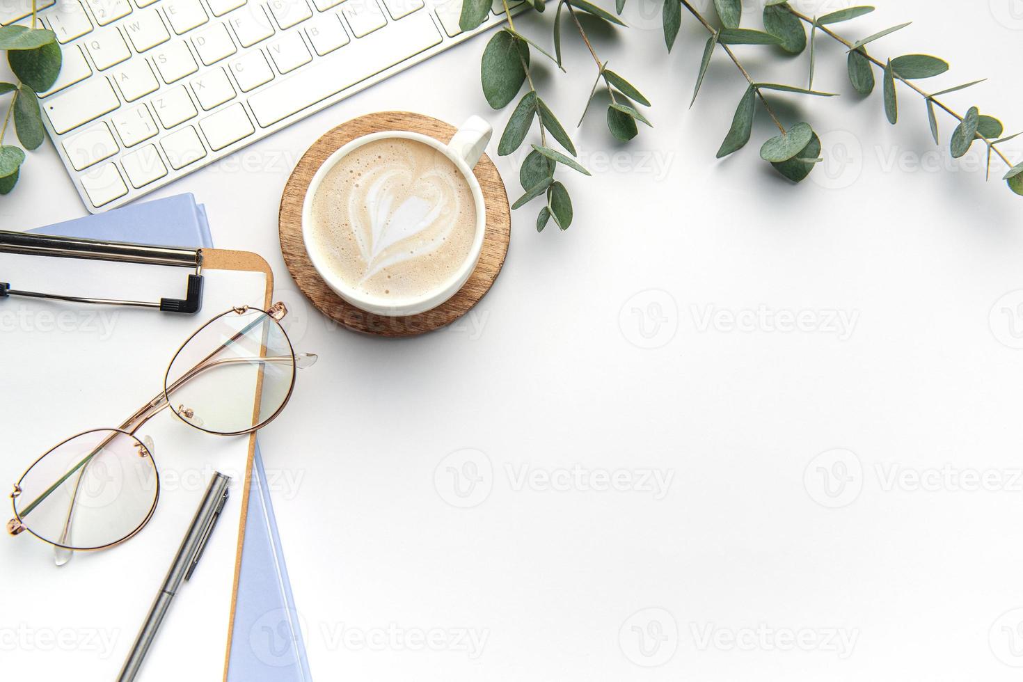 Modern white office desk table with laptop, notebook and other supplies. photo