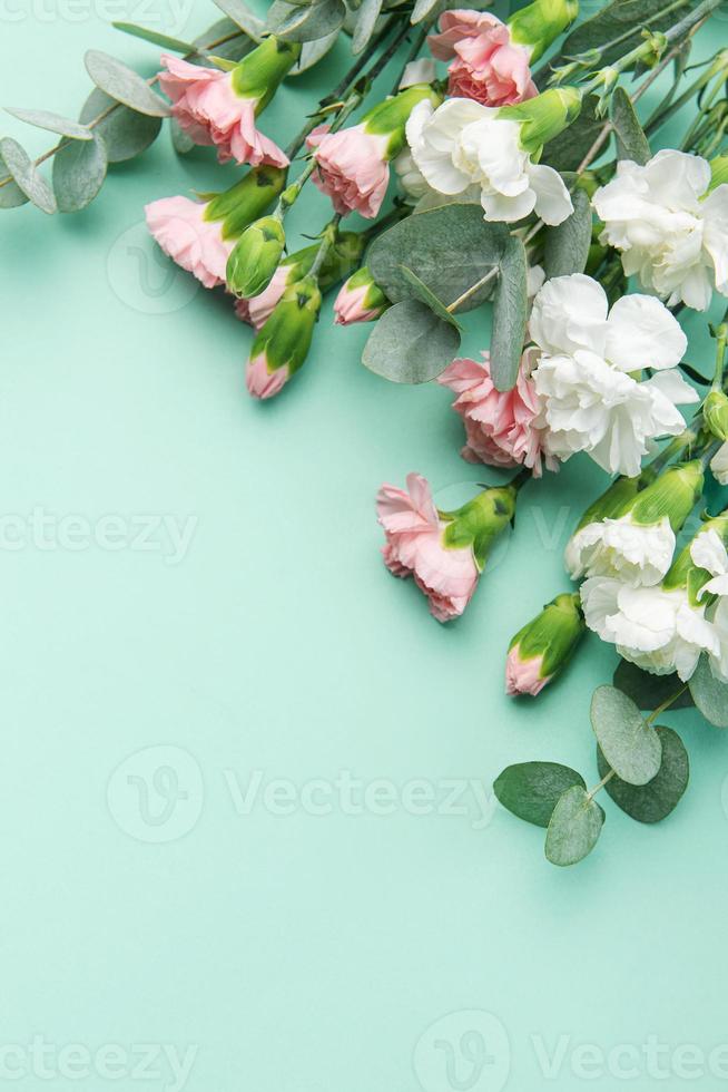 A bouquet of white and pink carnations with eucalyptus branches on a soft green background. photo