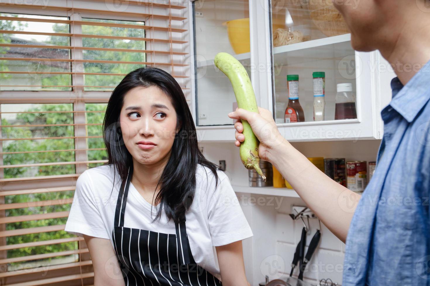 Asian couples cook together in the kitchen at home. They enjoyed playing and teasing each other. Man holding eggplant. Cooking family concept, starting a couple life Family building photo