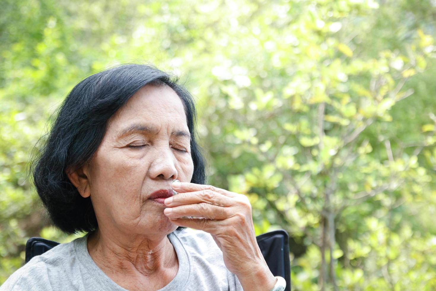 mayor asiático mujer viaje naturaleza ella estaba cansado, sentado y inhalando el inhalador a recuperar. con Copiar espacio. foto