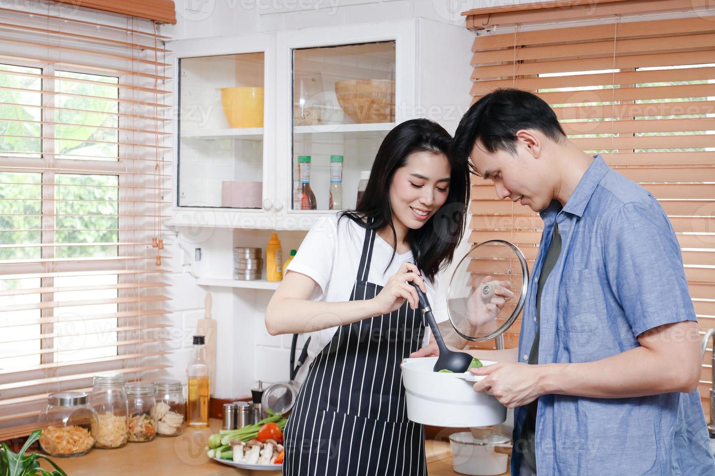 Asian couples enjoy cooking together in their home kitchen. Living concept during COVID 19, social distance, copy space photo