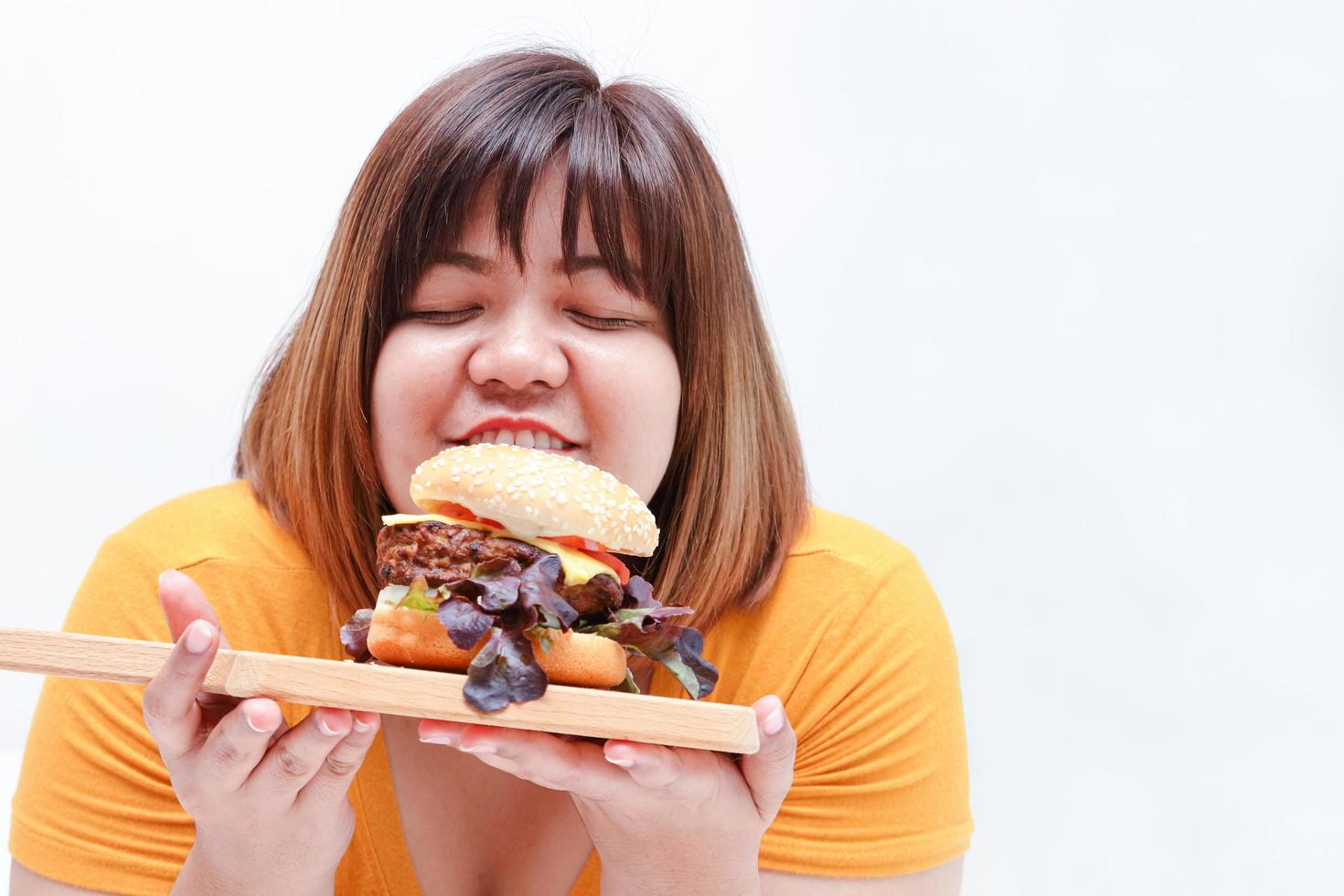 grasa asiático mujer comer grande hamburguesas, blanco antecedentes. salud concepto. personas quien son exceso de peso. foto