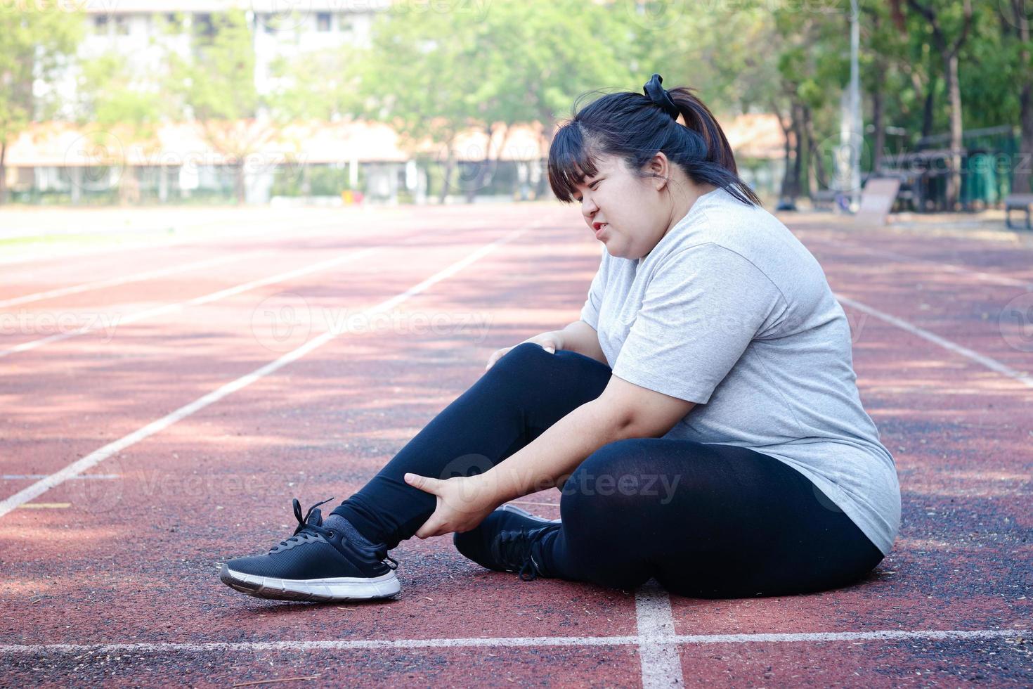 Fat Asian woman injured from jogging Sitting on the floor, holding the right ankle, felt a lot of pain. Concepts of weight loss, exercise, health problems photo
