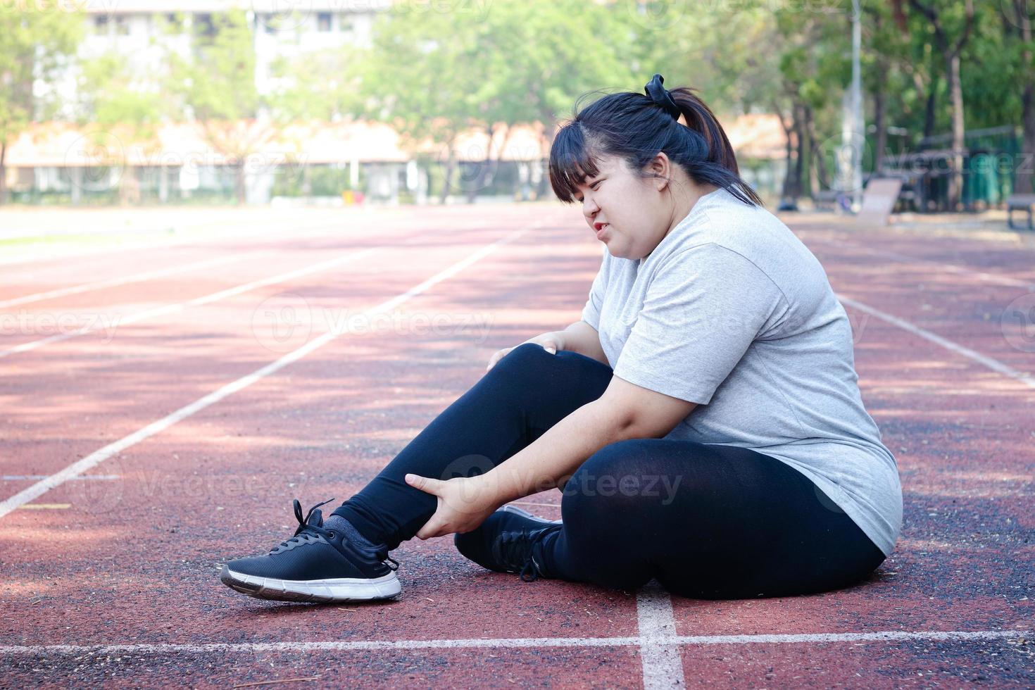 grasa asiático mujer lesionado desde trotar sentado en el piso, participación el Derecha tobillo, sintió un lote de dolor. conceptos de peso pérdida, ejercicio, salud problemas foto