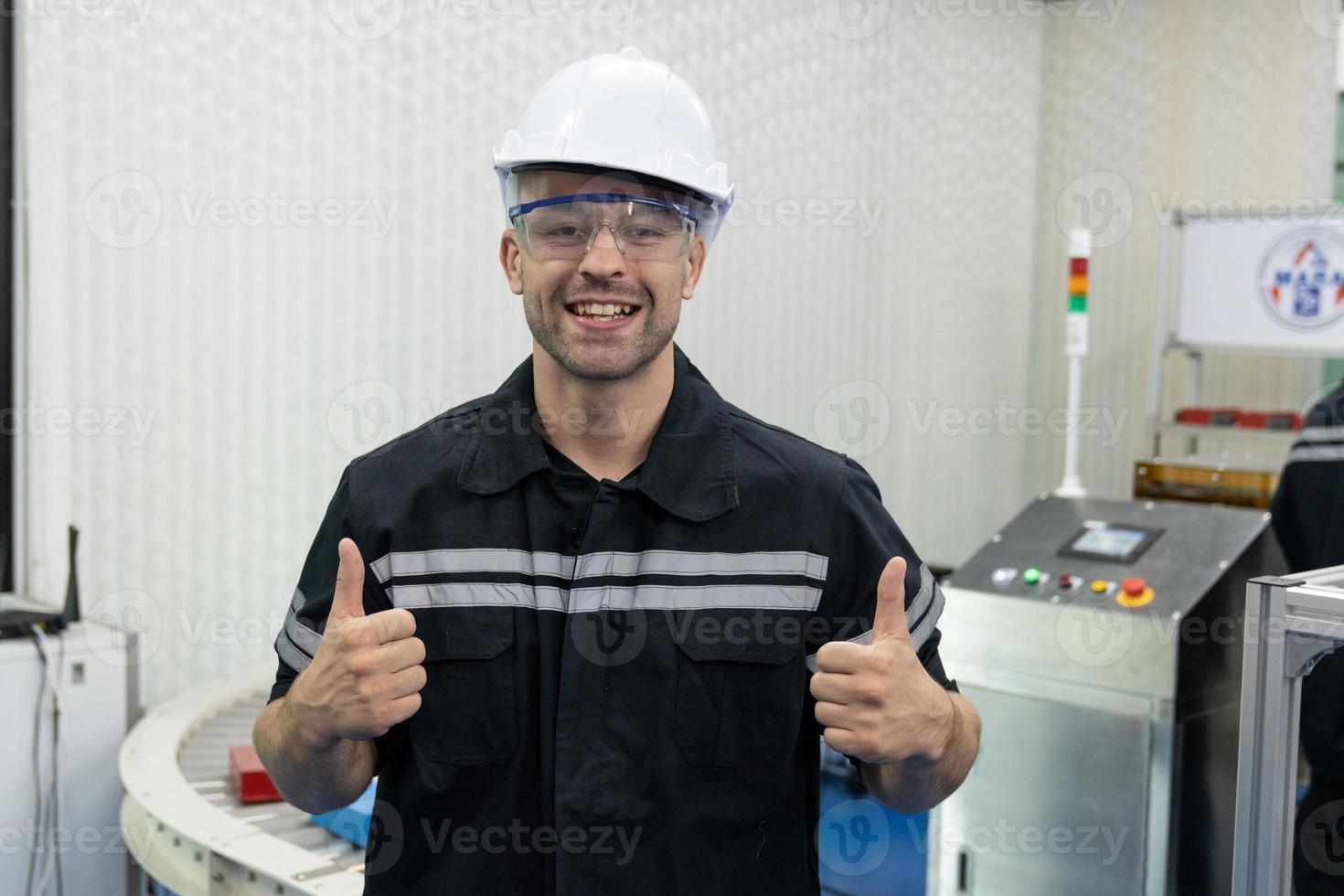 Portrait of an Indian male engineer with helmet and safety glasses showing thumbs up photo