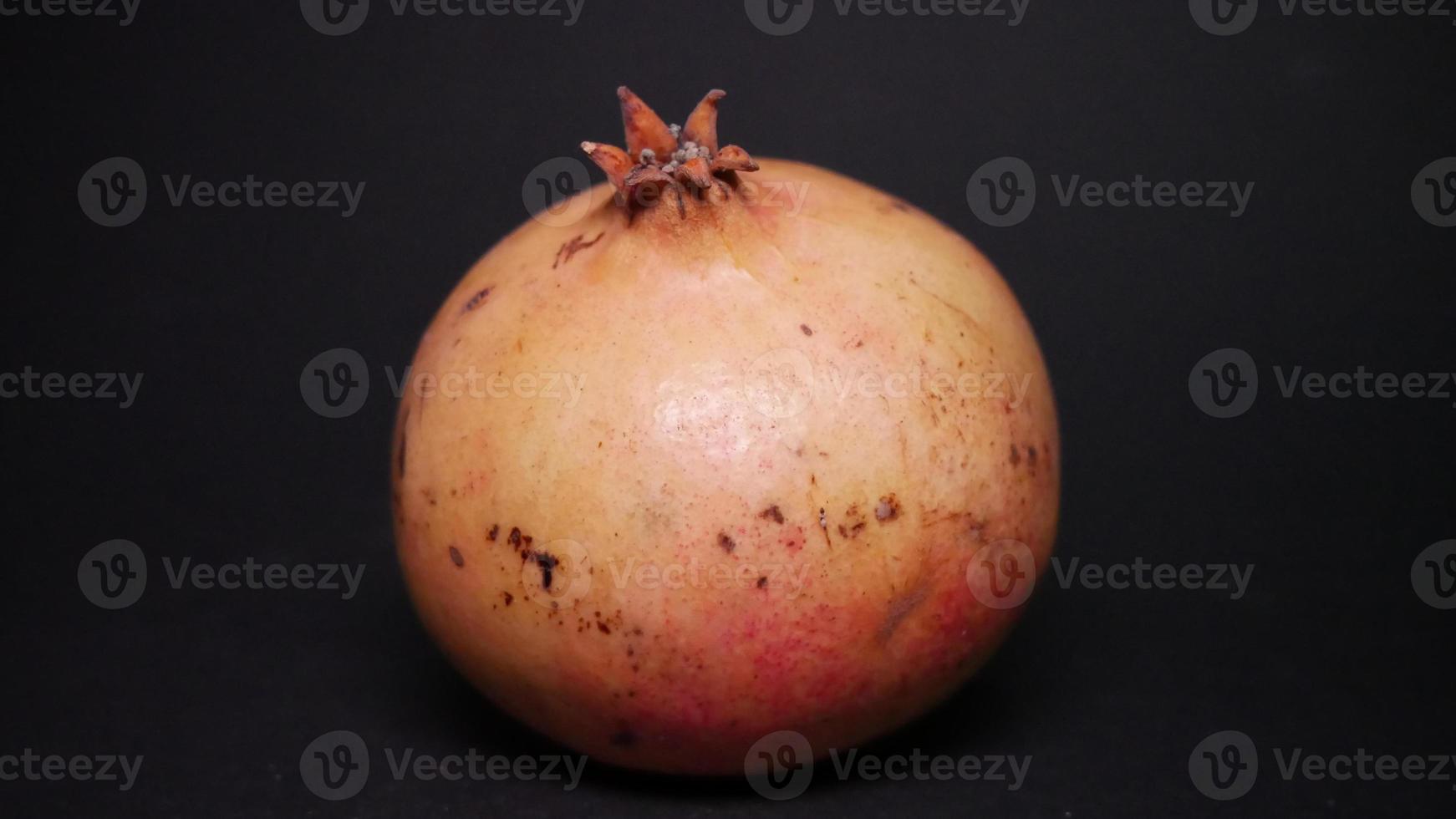 Ripe pomegranate   on  a black background photo