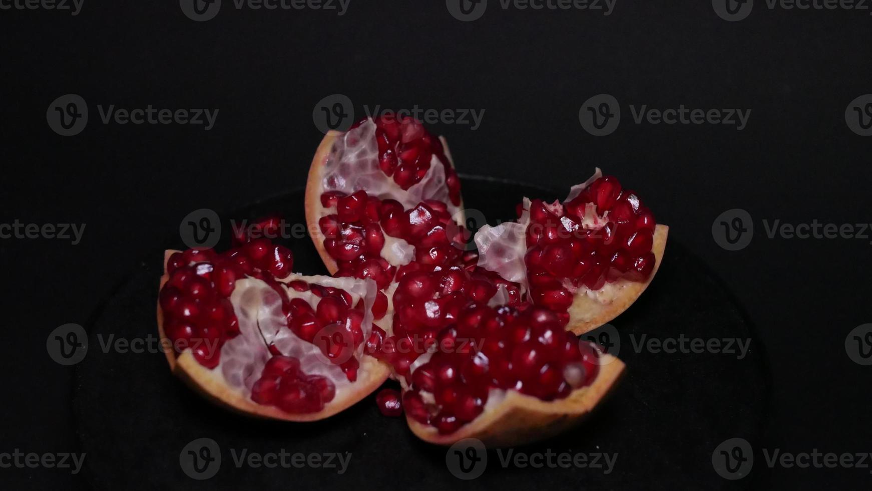 Ripe pomegranate   on  a black background photo