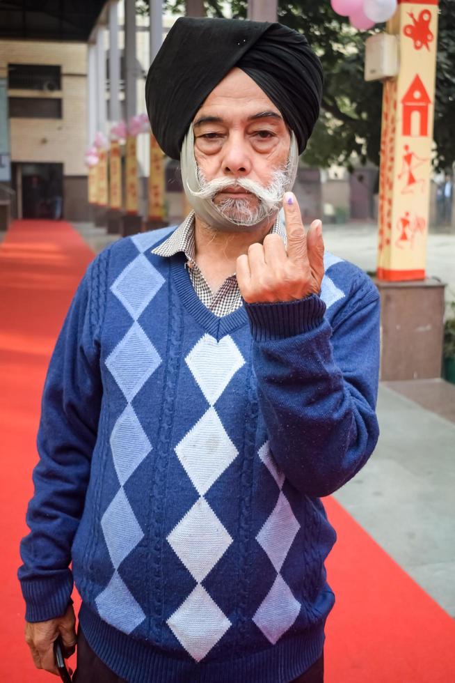 New Delhi, India - December 04 2022 - Unidentified people showing their ink-marked fingers after casting votes in front of polling booth of east Delhi area for MCD local body Elections 2022 photo