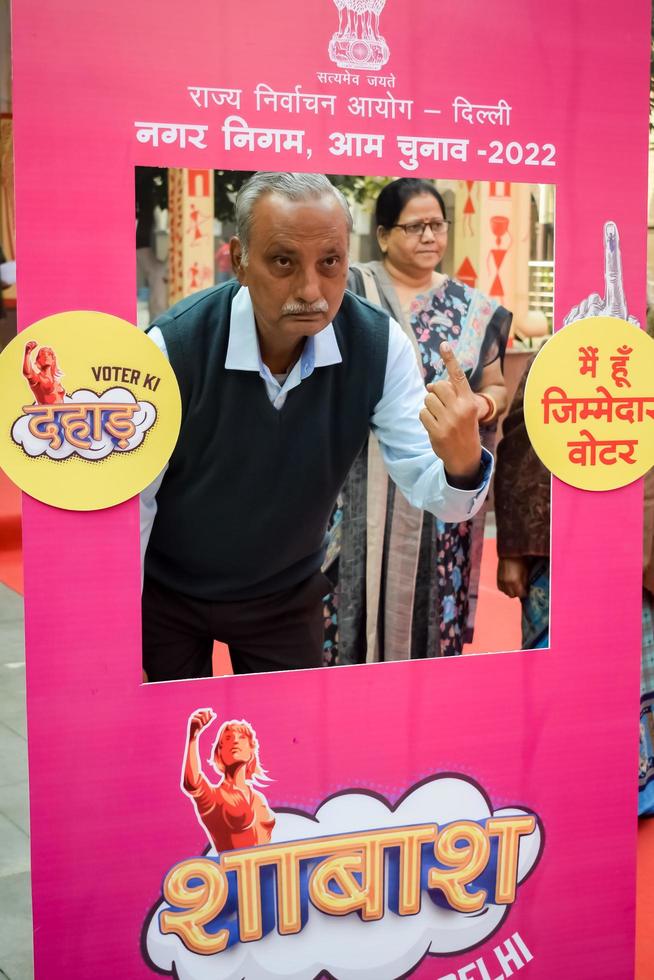 New Delhi, India - December 04 2022 - Unidentified people showing their ink-marked fingers after casting votes in front of polling booth of east Delhi area for MCD local body Elections 2022 photo