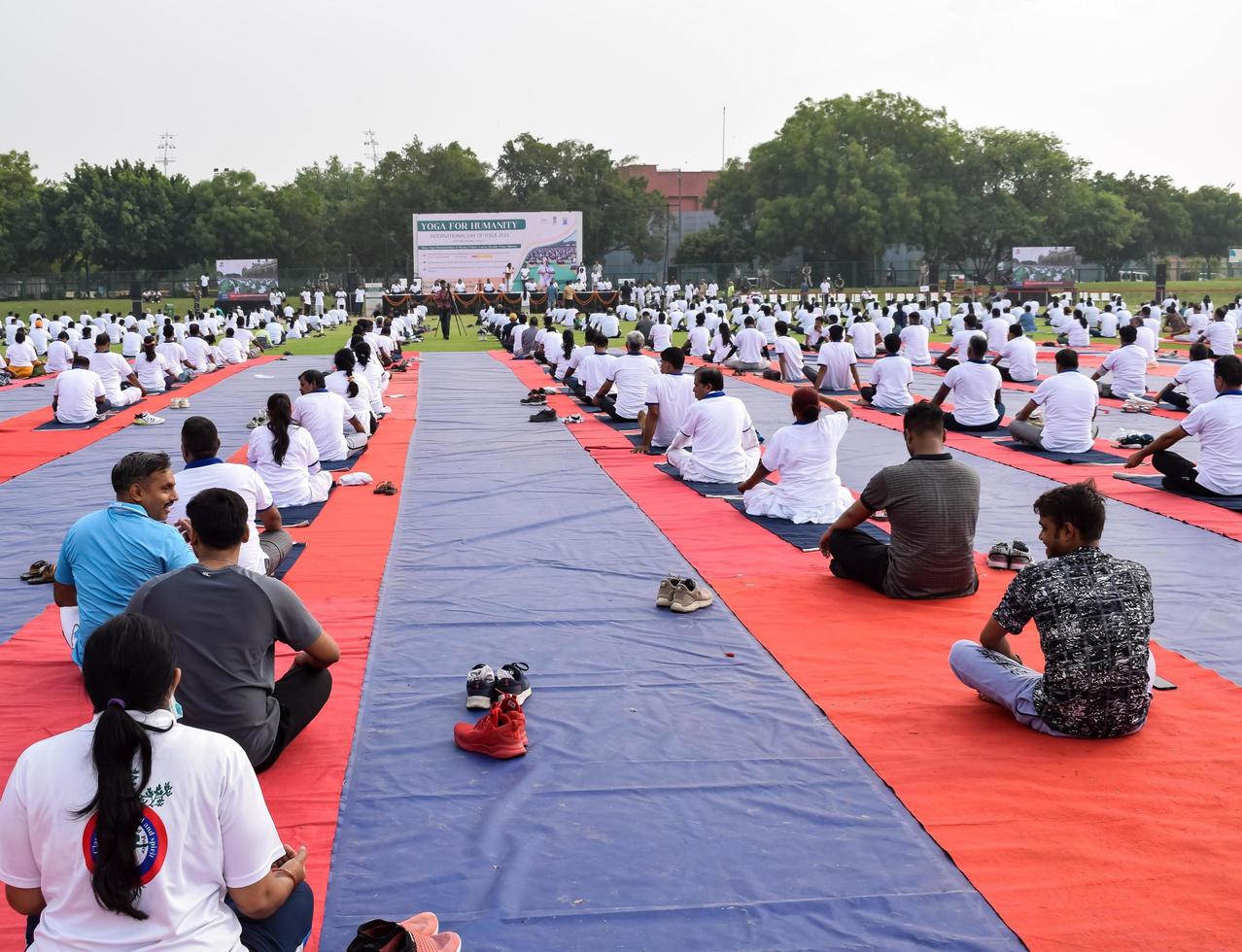 New Delhi, India, June 21 2022 - Group Yoga exercise session for people at Yamuna Sports Complex in Delhi on International Yoga Day, Big group of adults attending yoga class in cricket stadium photo