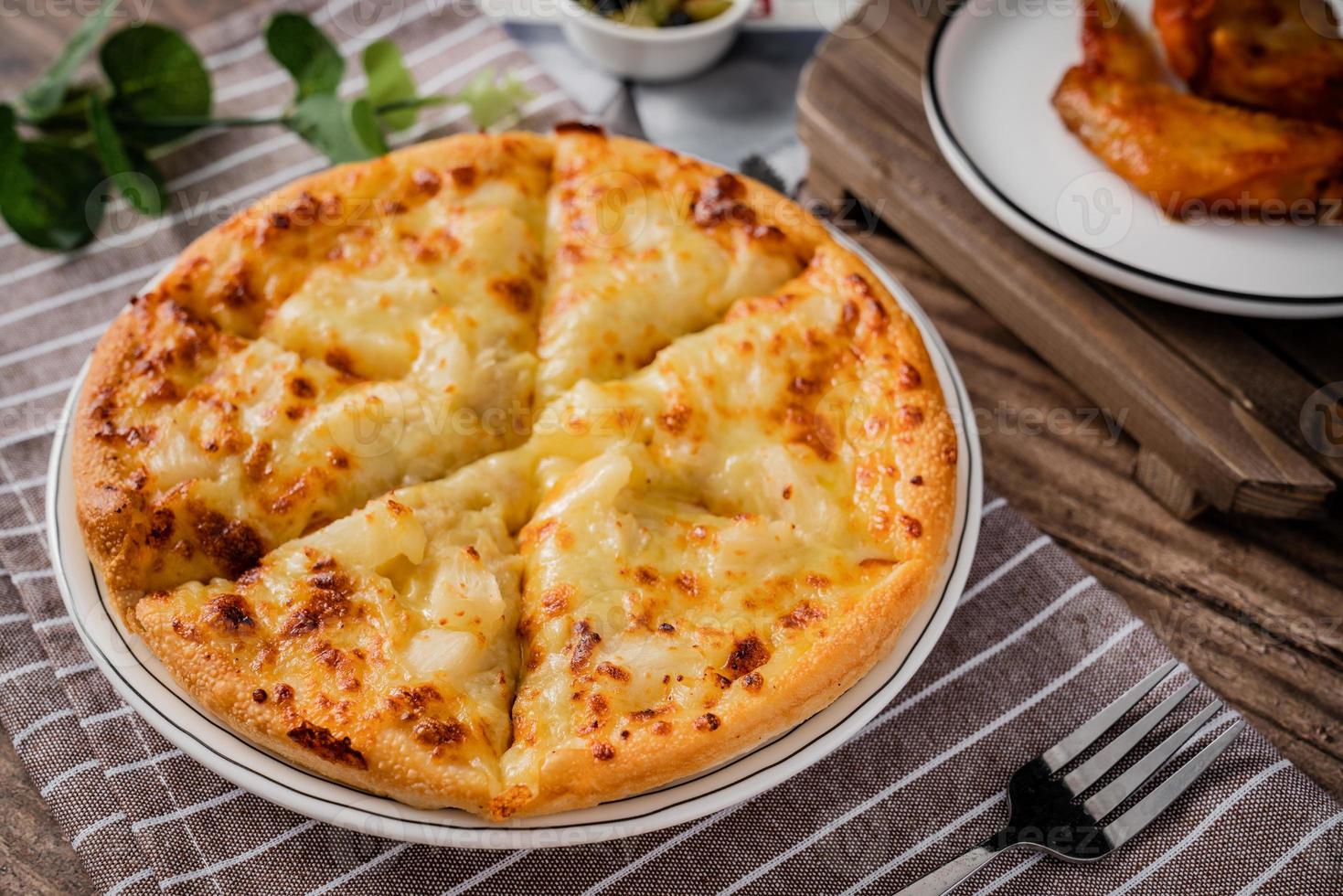 classic pizza with cheese on the table in a cafe on a wooden stand with a cut triangular piece and a pizza knife photo