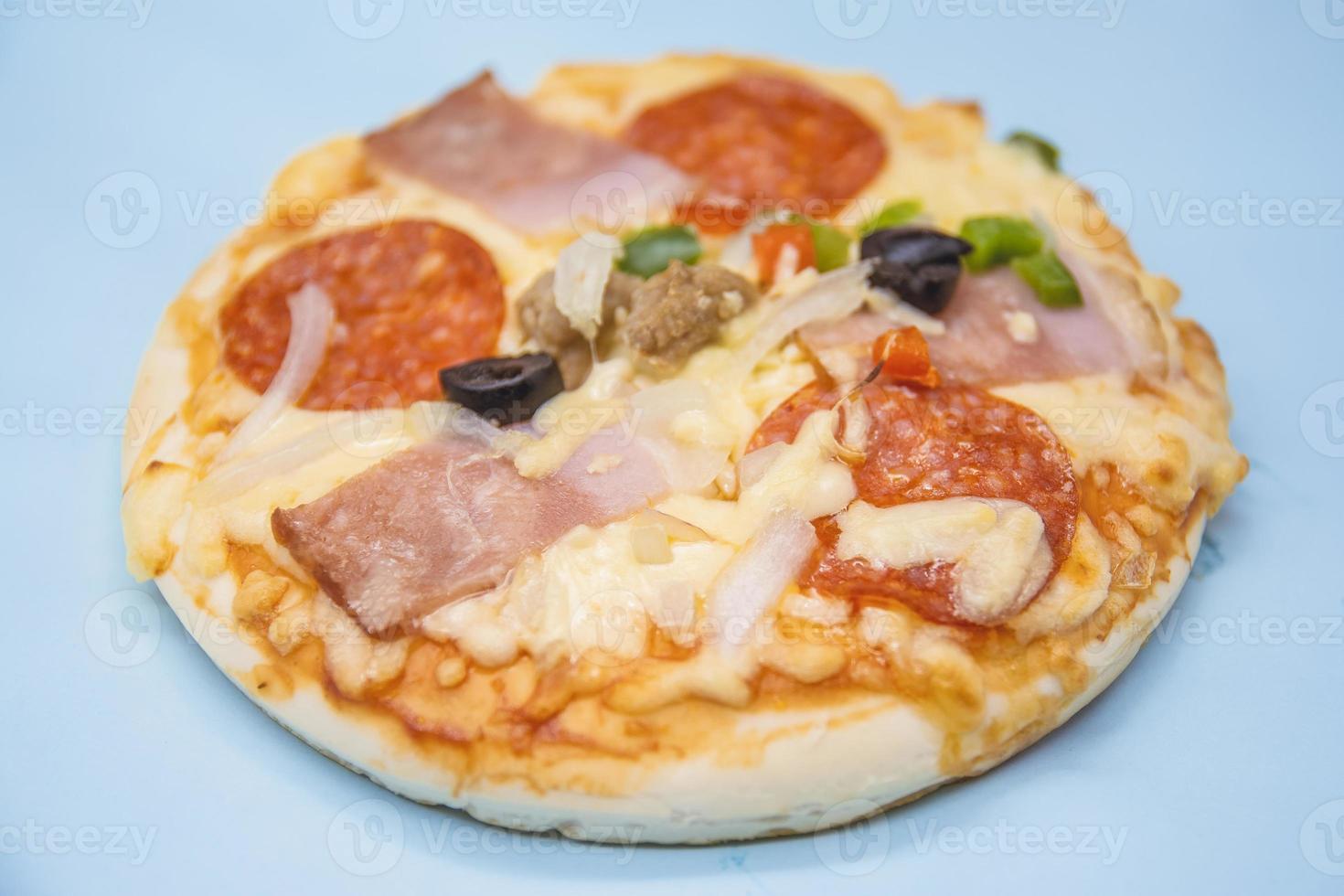 classic pizza with cheese on the table in a cafe on a wooden stand with a cut triangular piece and a pizza knife photo