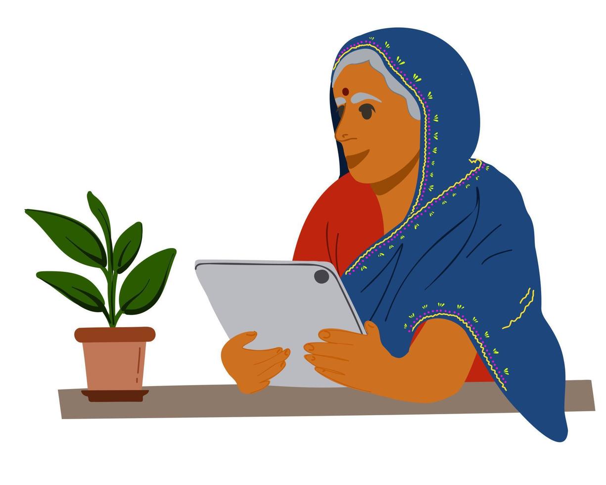 An elderly Indian woman sits at a table with a tablet. vector