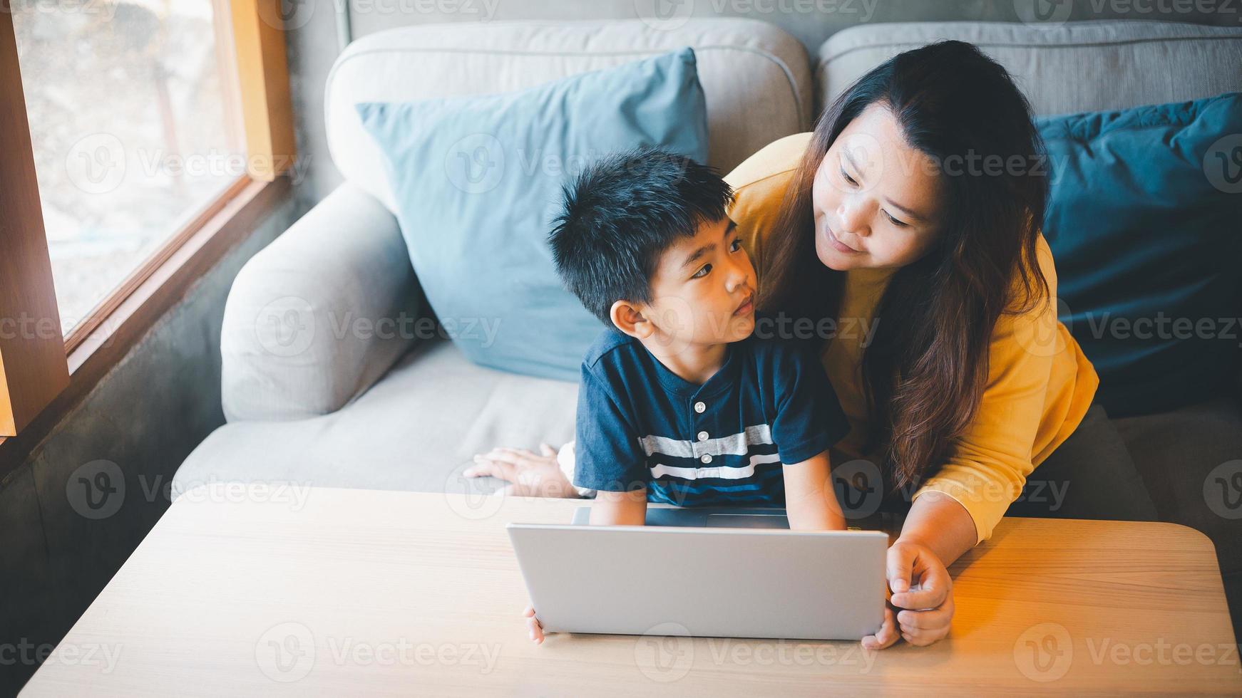 madre y hijo acecho alguna cosa en pantalla mientras estudiando a un café tienda utilizando su ordenador portátil a estudiar en línea durante el covid-19 aislamiento. en línea educación, educación en el hogar foto