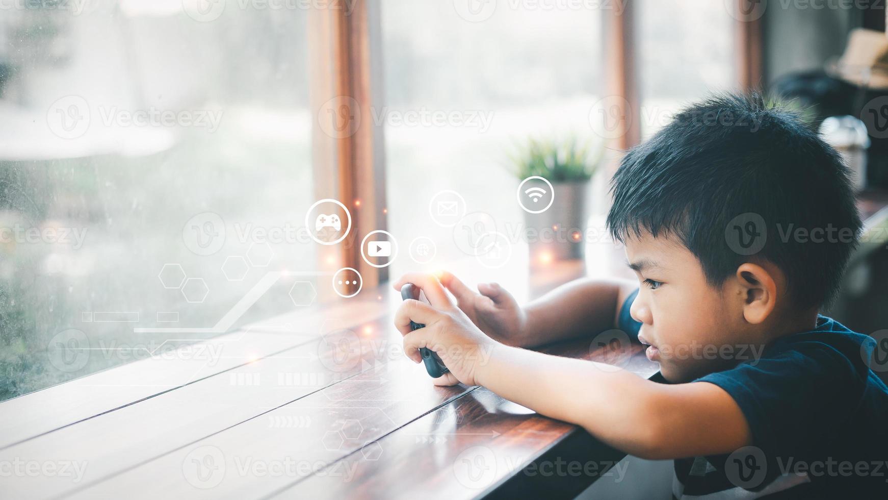 Handsome Asian man sits at home by a glass window with a mobile phone at home. Using various media with great enthusiasm serious look. Online education, Homeschooling. photo