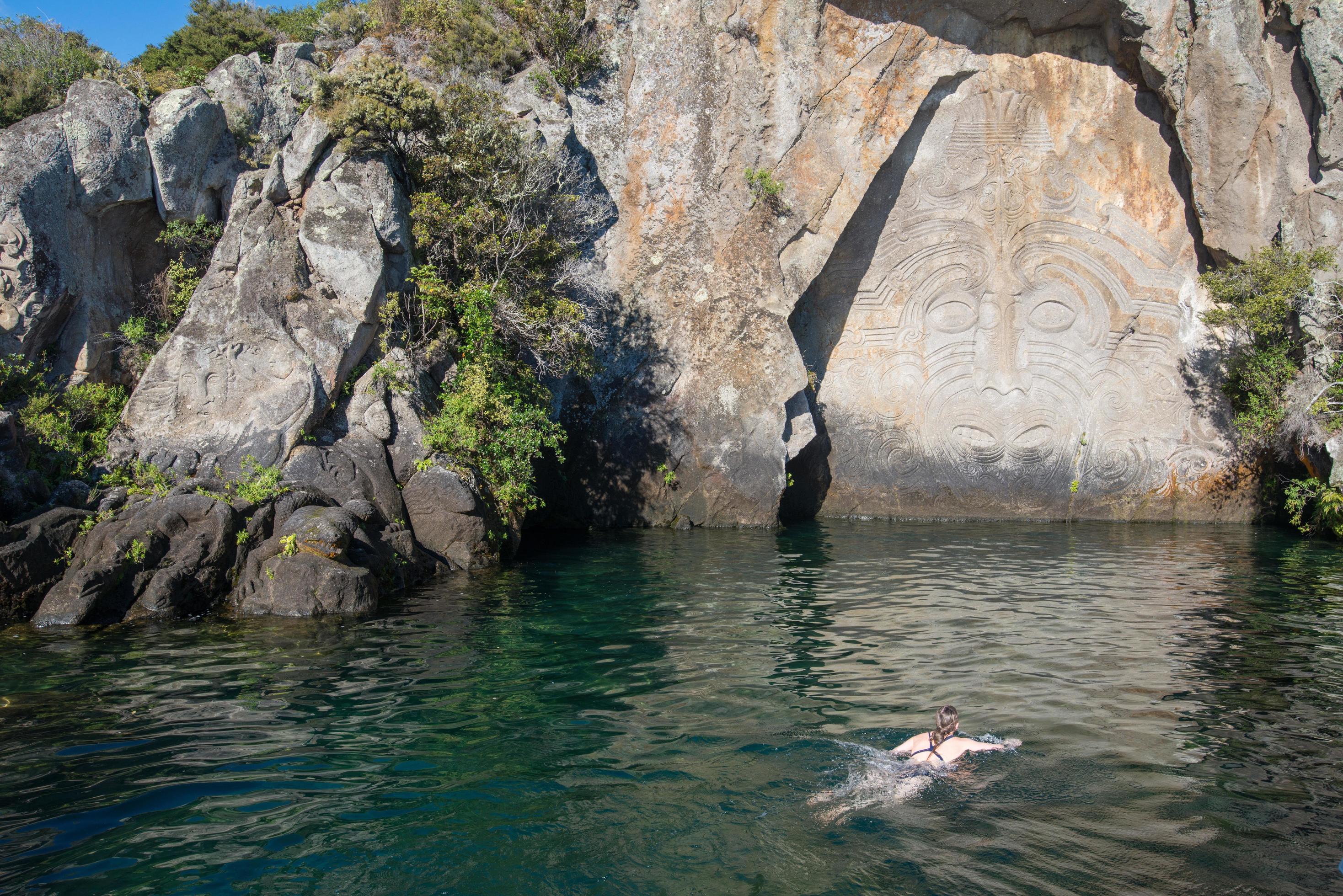 turista nadando en genial lago taupo con maorí rock tallas el icónico