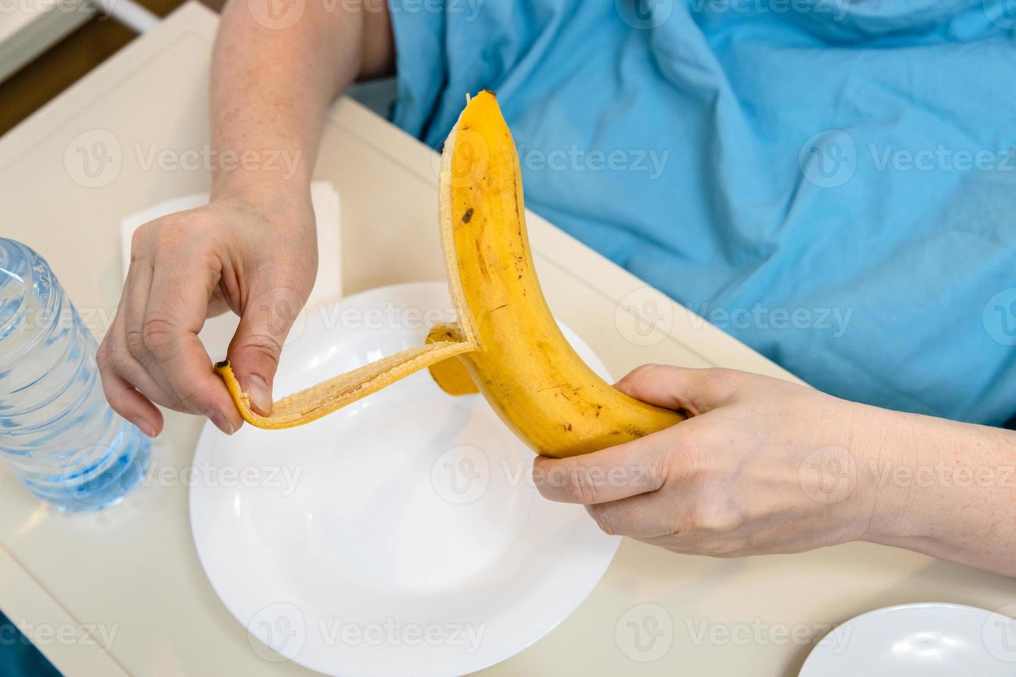 patient peels banana close up in hospital bed photo