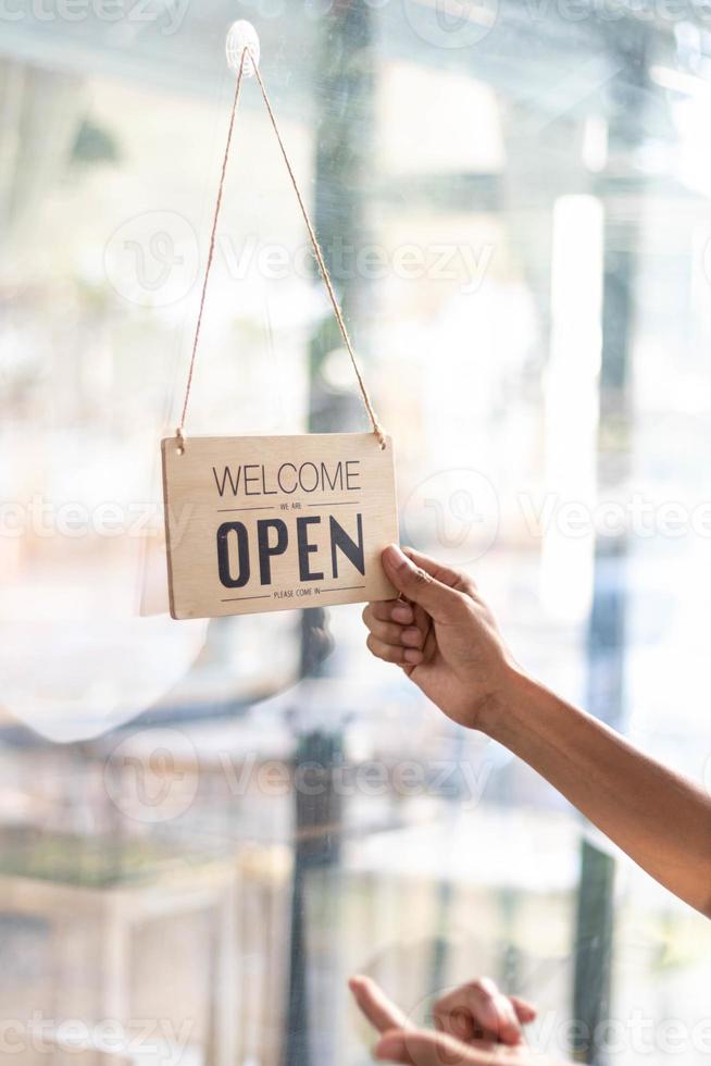 café tienda empleados son voltear Tienda apertura firmar instalado en vaso frente puerta entonces ese clientes lata ver Tienda apertura firmar y utilizar el Servicio dentro el café tienda. puesta en marcha negocio concepto. foto