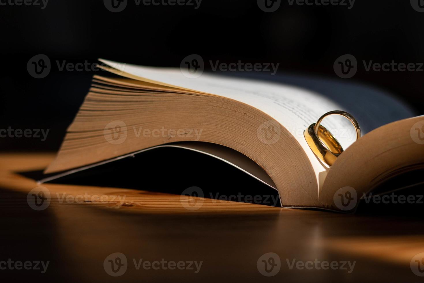 Two wedding rings are placed on the open Bible placed on the table as wedding rings prepared for lovers to wear and read Bible passages as a promise to each other. Copy Space for text photo