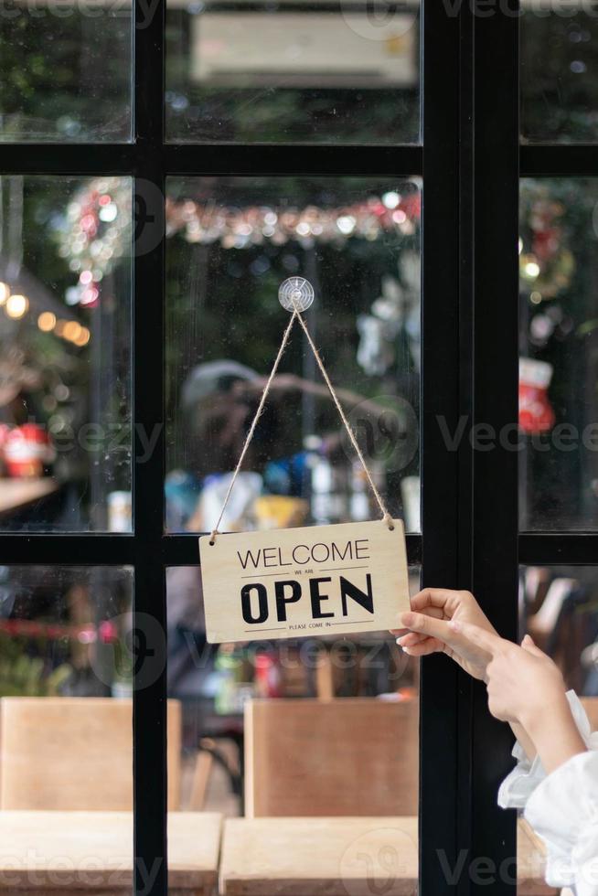 café tienda empleados son voltear Tienda apertura firmar instalado en vaso frente puerta entonces ese clientes lata ver Tienda apertura firmar y utilizar el Servicio dentro el café tienda. puesta en marcha negocio concepto. foto