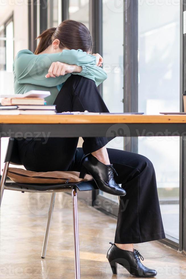 A businessman who is tired and stressed from continuous work for a long time is laying down her head on her arm to relieve stress. The concept of stress caused by long periods of work. photo