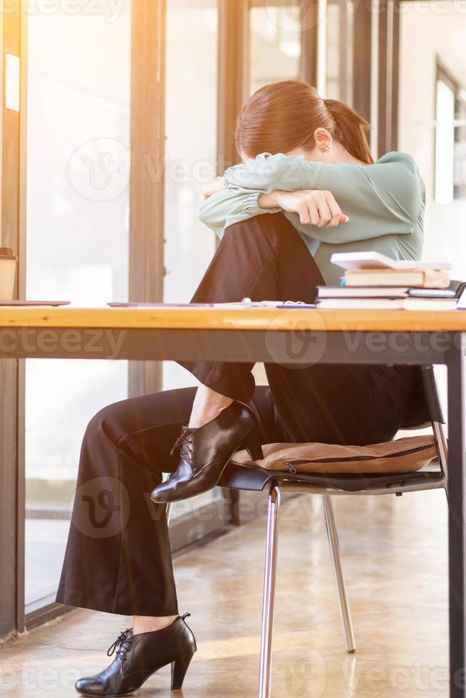 A businessman who is tired and stressed from continuous work for a long time is laying down her head on her arm to relieve stress. The concept of stress caused by long periods of work. photo