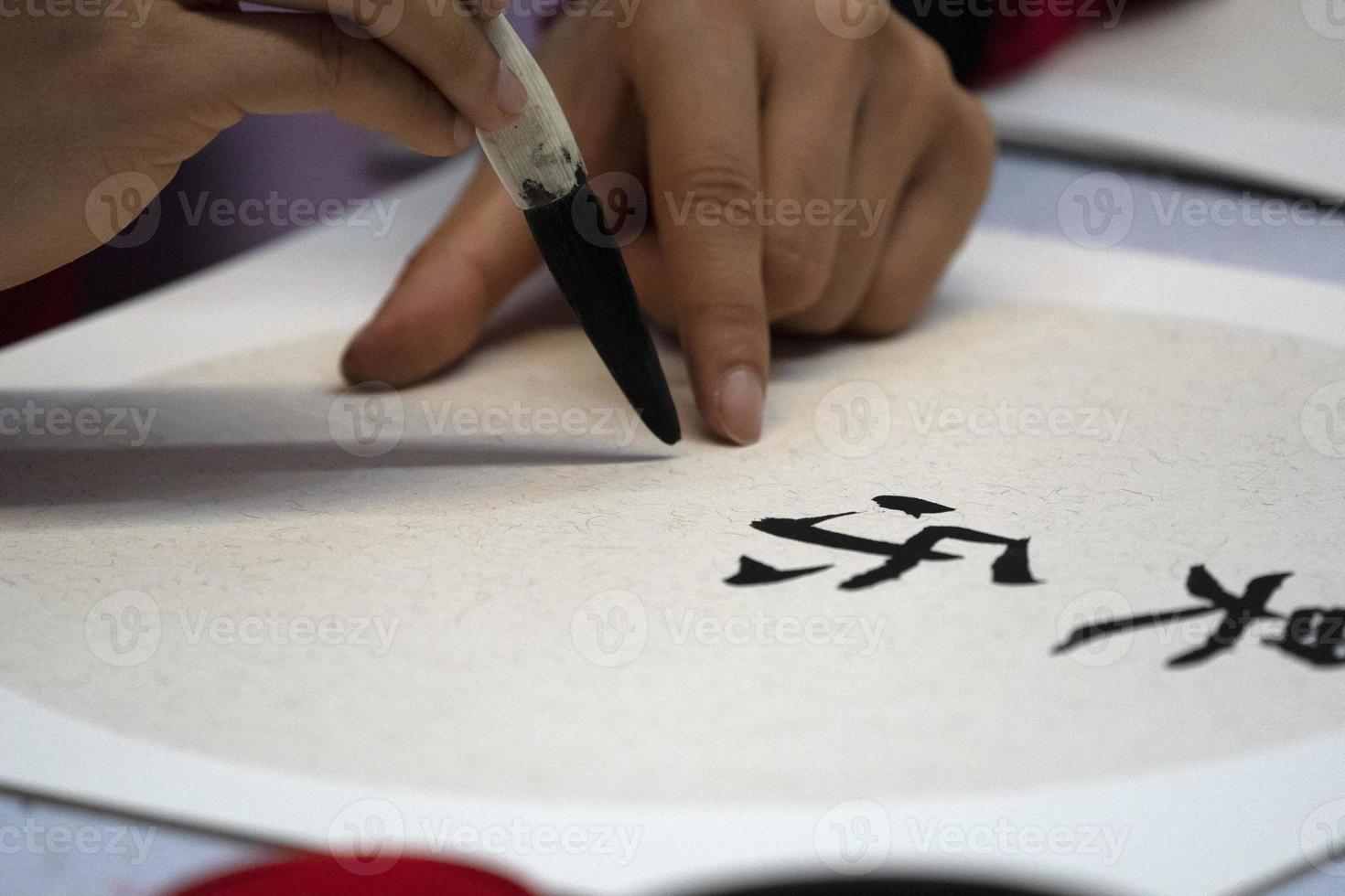 japanese woman writing name Charles in ideograms with brush photo