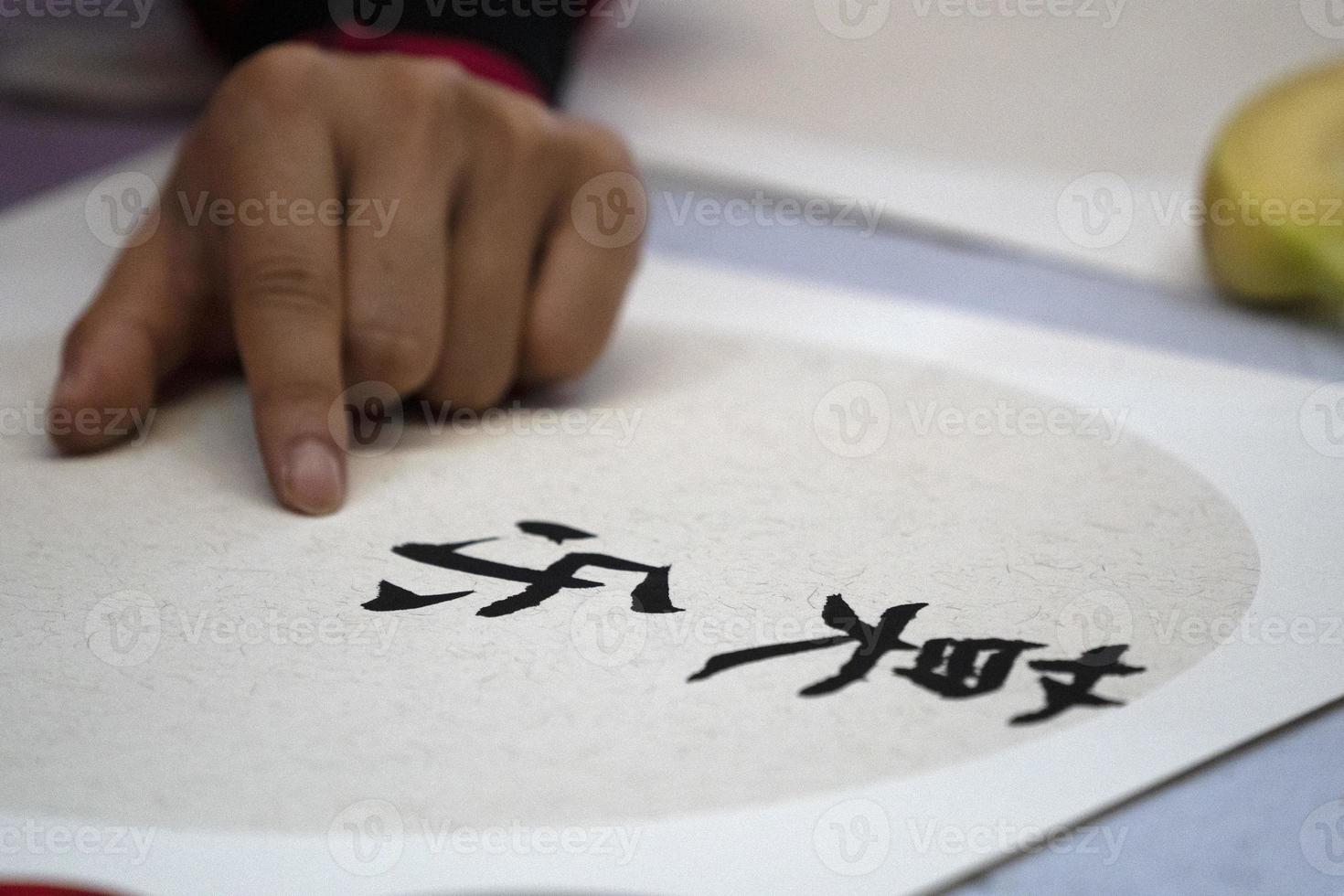 japanese woman writing name Charles in ideograms with brush photo