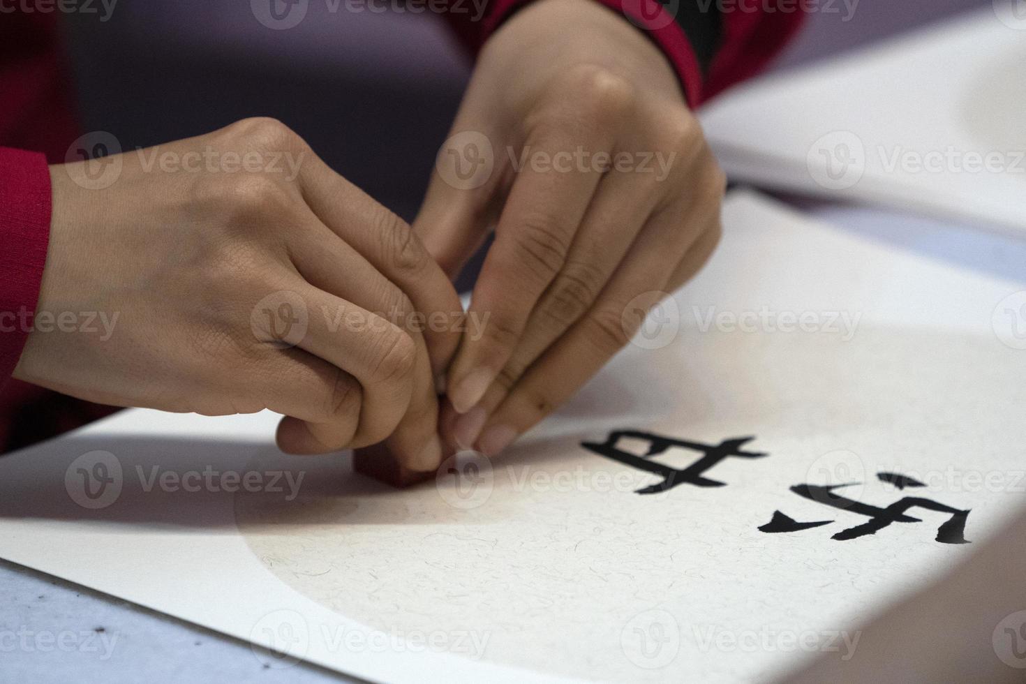 japanese woman writing name Charles in ideograms with brush photo