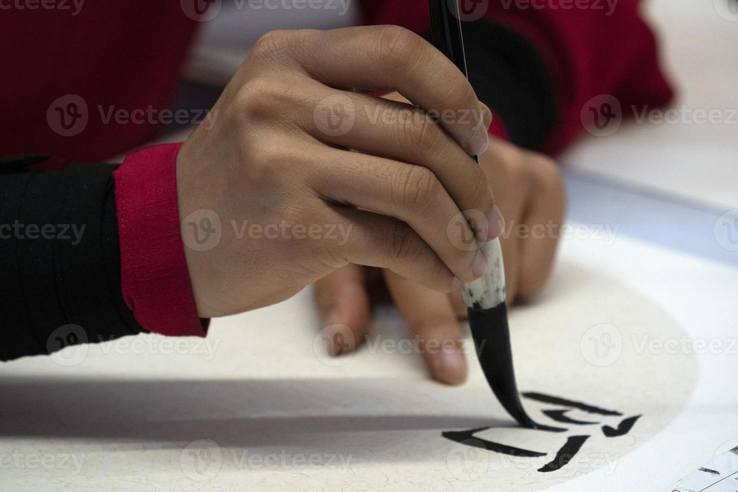 japanese woman writing name Diana in ideograms with brush photo