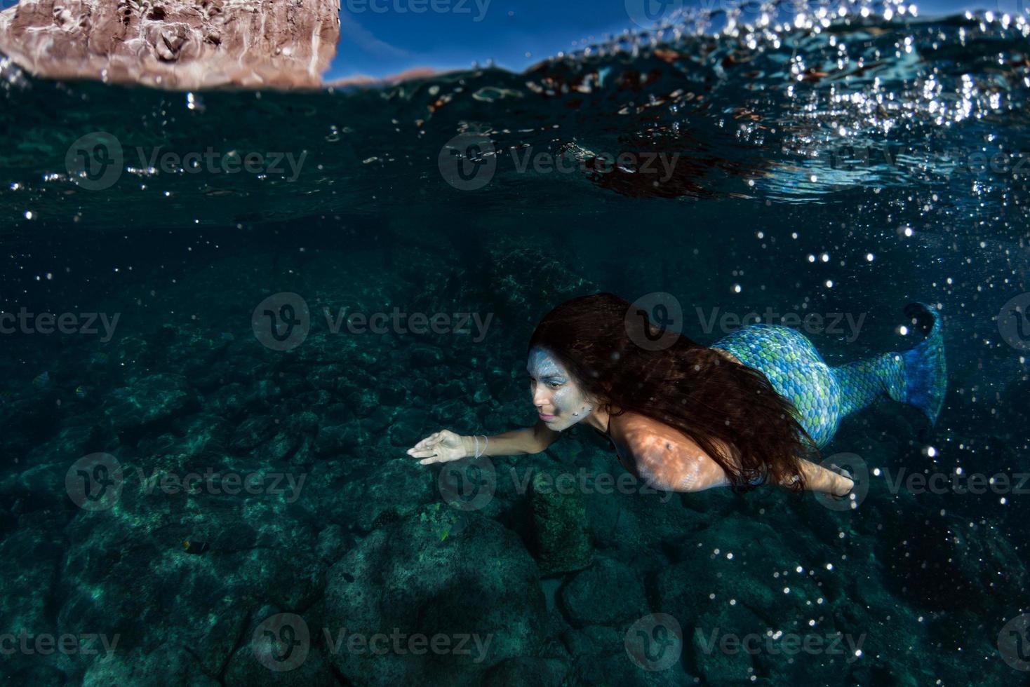 sirena nadando bajo el agua en el mar azul profundo foto