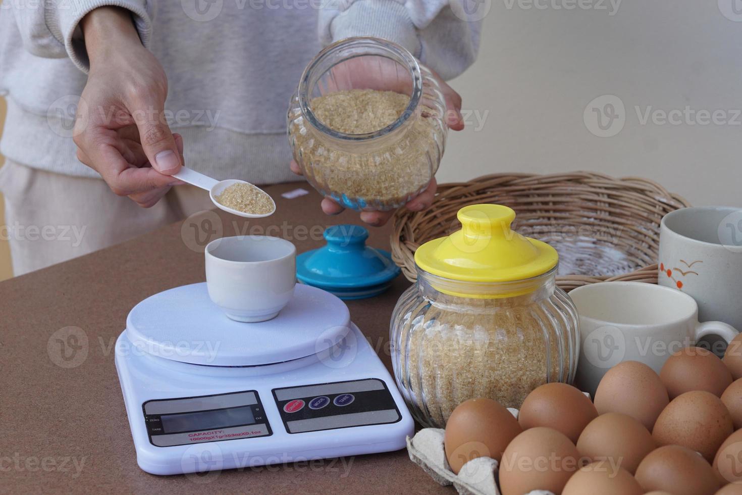 la mano de primer plano escala el azúcar para cocinar, prepara huevos y otros ingredientes alimentarios para hacer galletas. concepto, cocina, panadería. Me encanta cocinar estilo de vida. actividad de pasatiempo. cocina foto