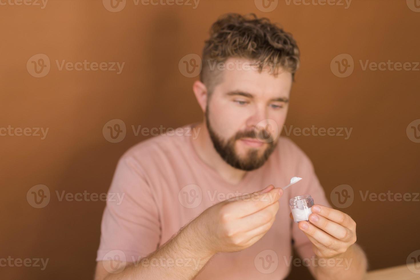 Man talking on cosmetics holding a makeup tools while recording his video. Guy making video for his blog on cosmetic product photo