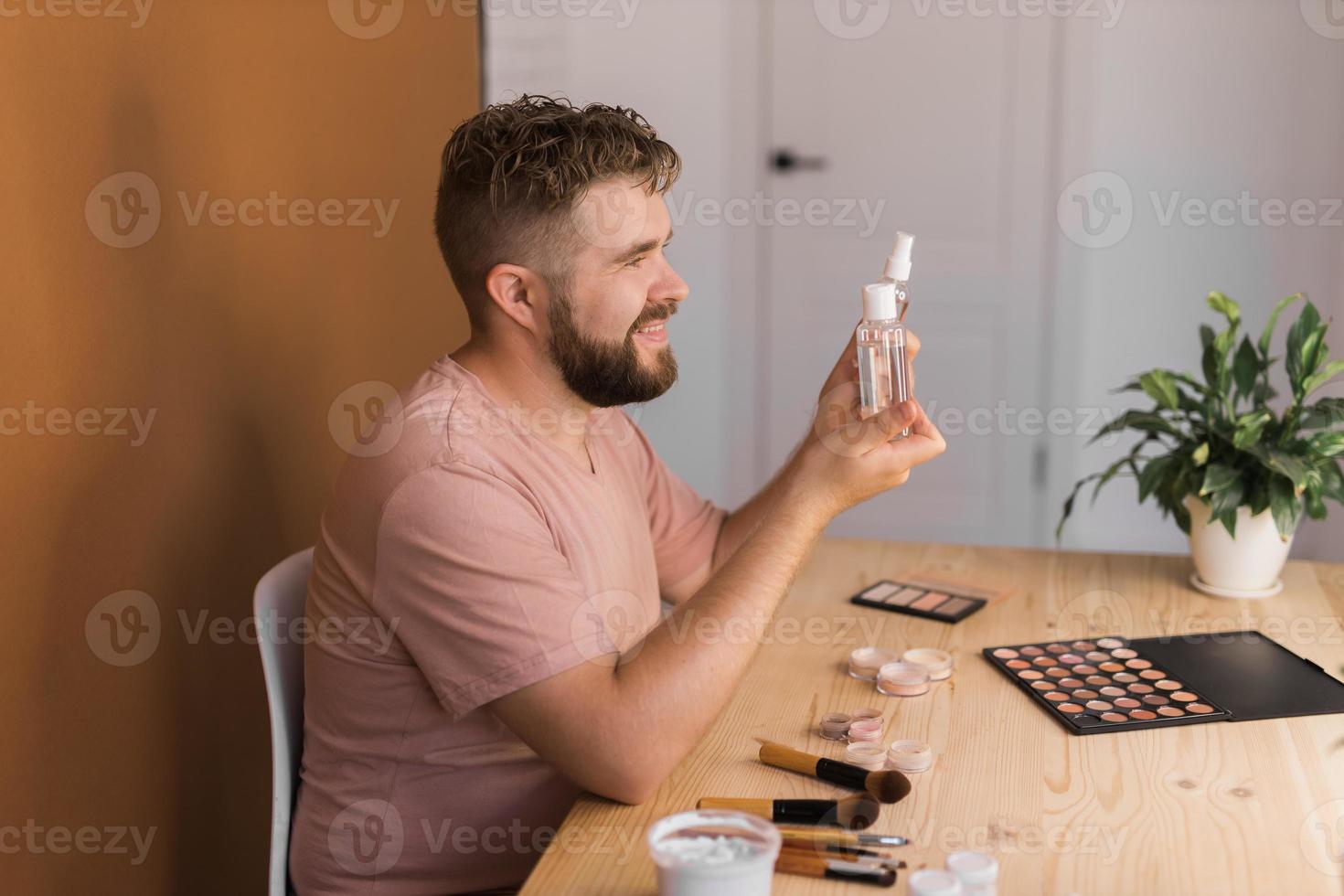 Man recording video vlog while applying cosmetics or explore cosmetic product. Guy making tutorial make-up for his blog on cosmetics. photo