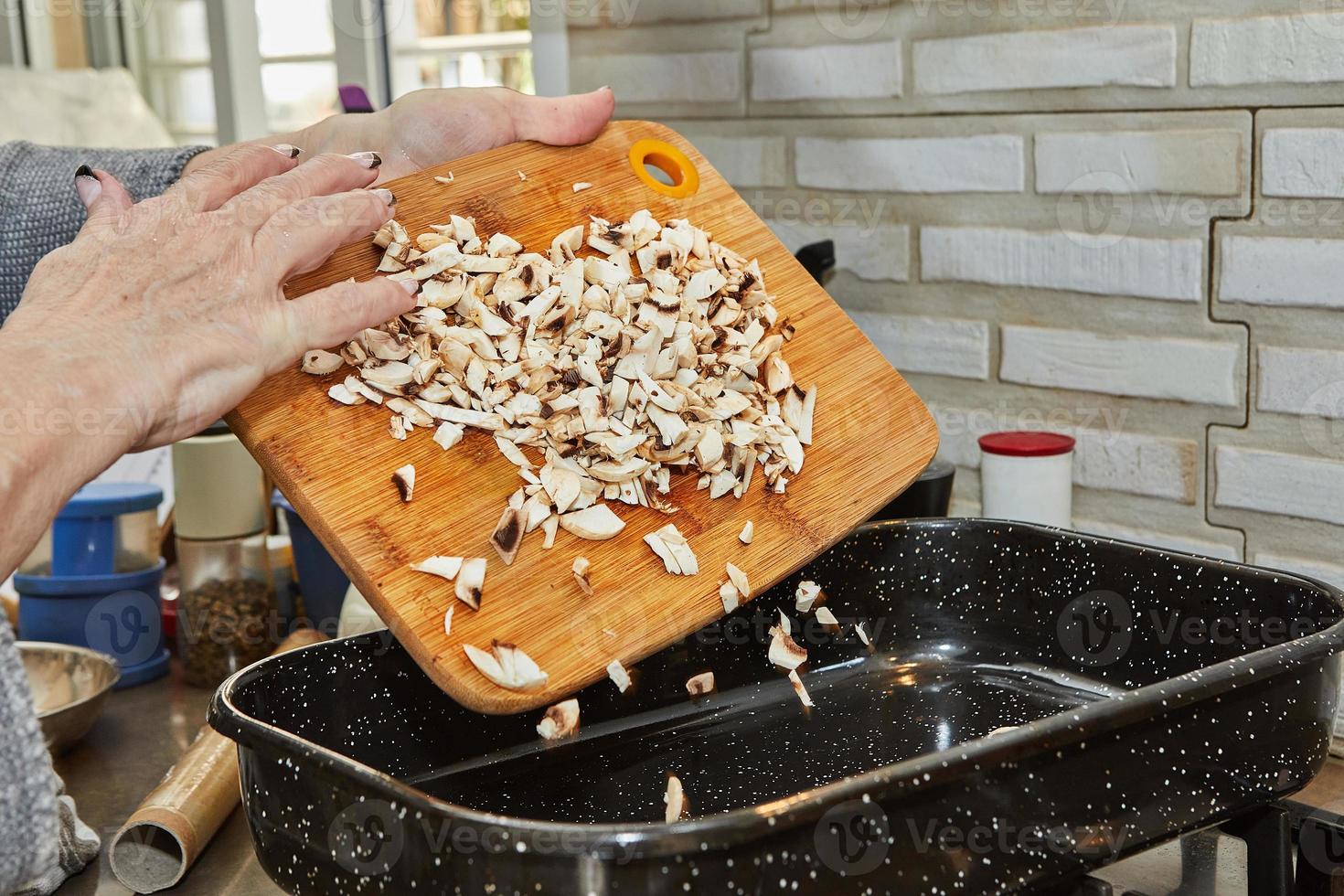 Cook throws mushrooms into square frying pan photo