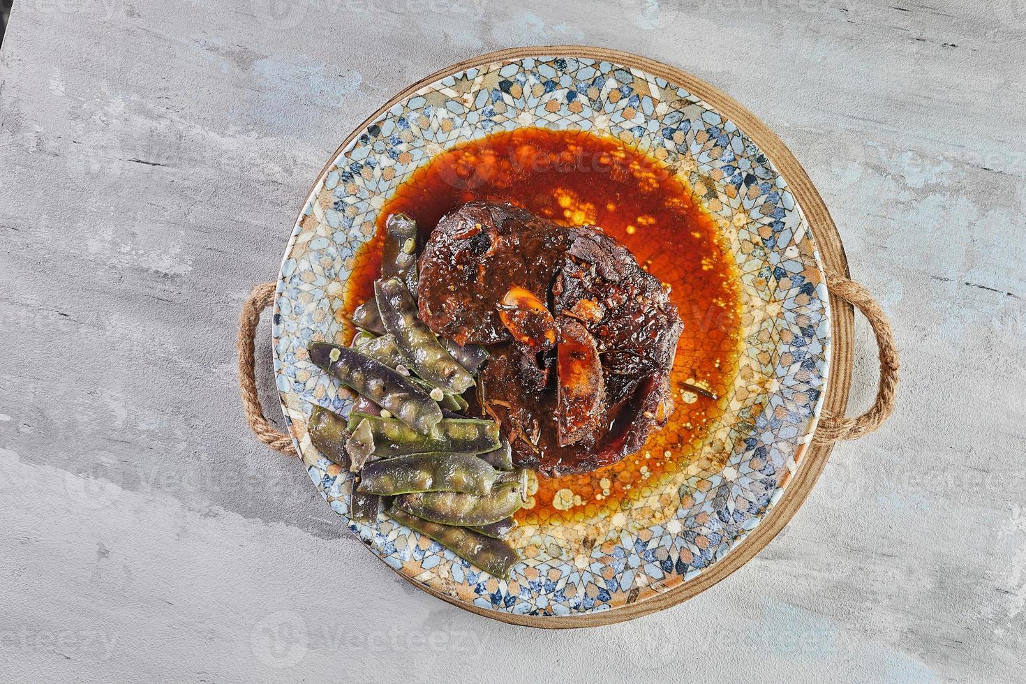 Lamb confit with snow peas in sauce on plate photo