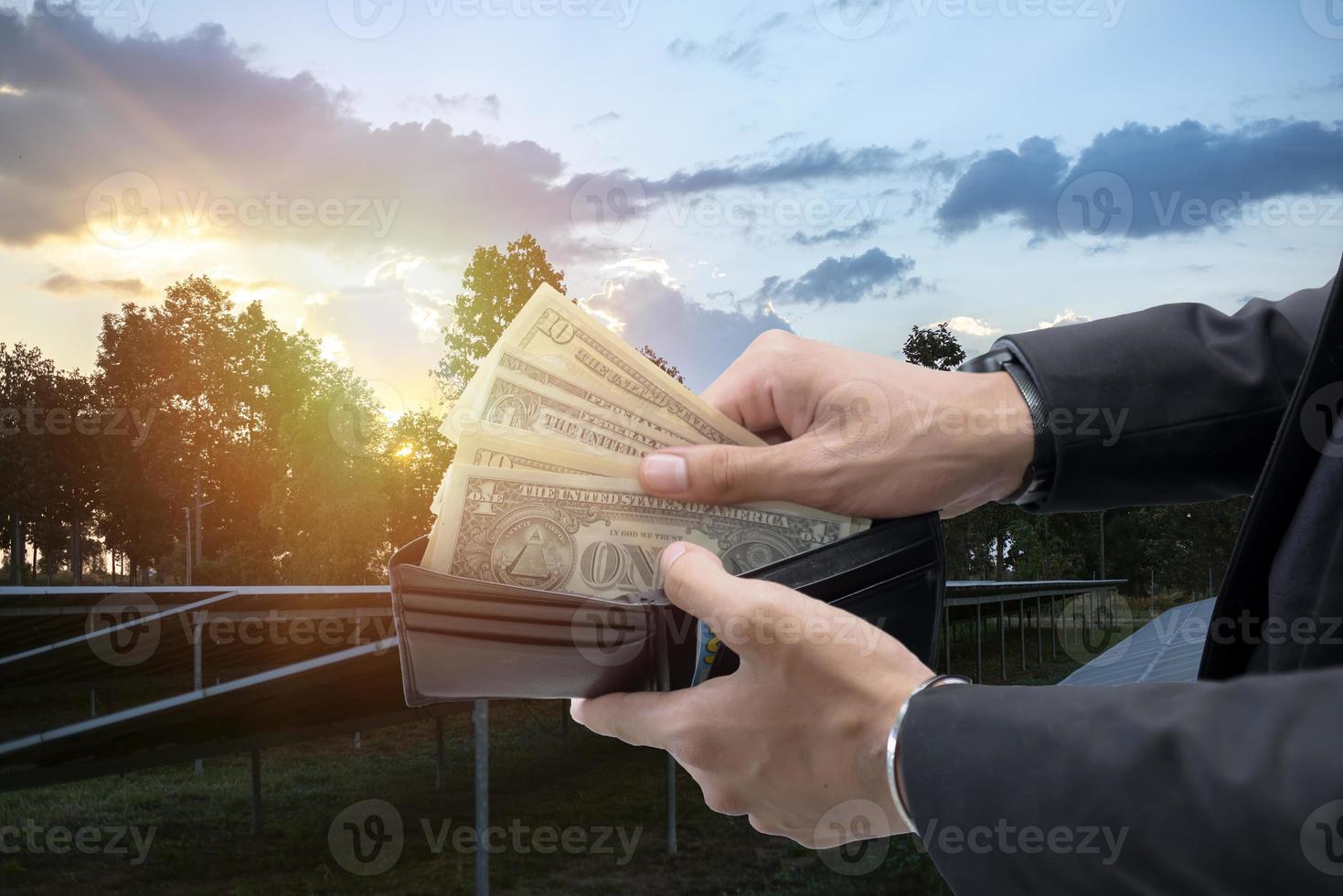 mano participación dólar cuentas ese Mira fuera de un billetera en un antecedentes de solar paneles ahorra dinero. utilizando solar energía. verde electricidad. foto