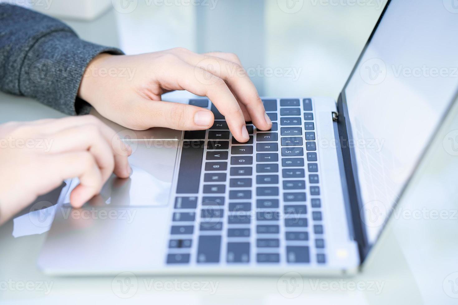 Woman working at home office using laptop searching web, browsing information photo