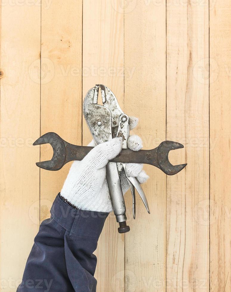 Hand in glove holding Spanner and Adjustable wrench photo