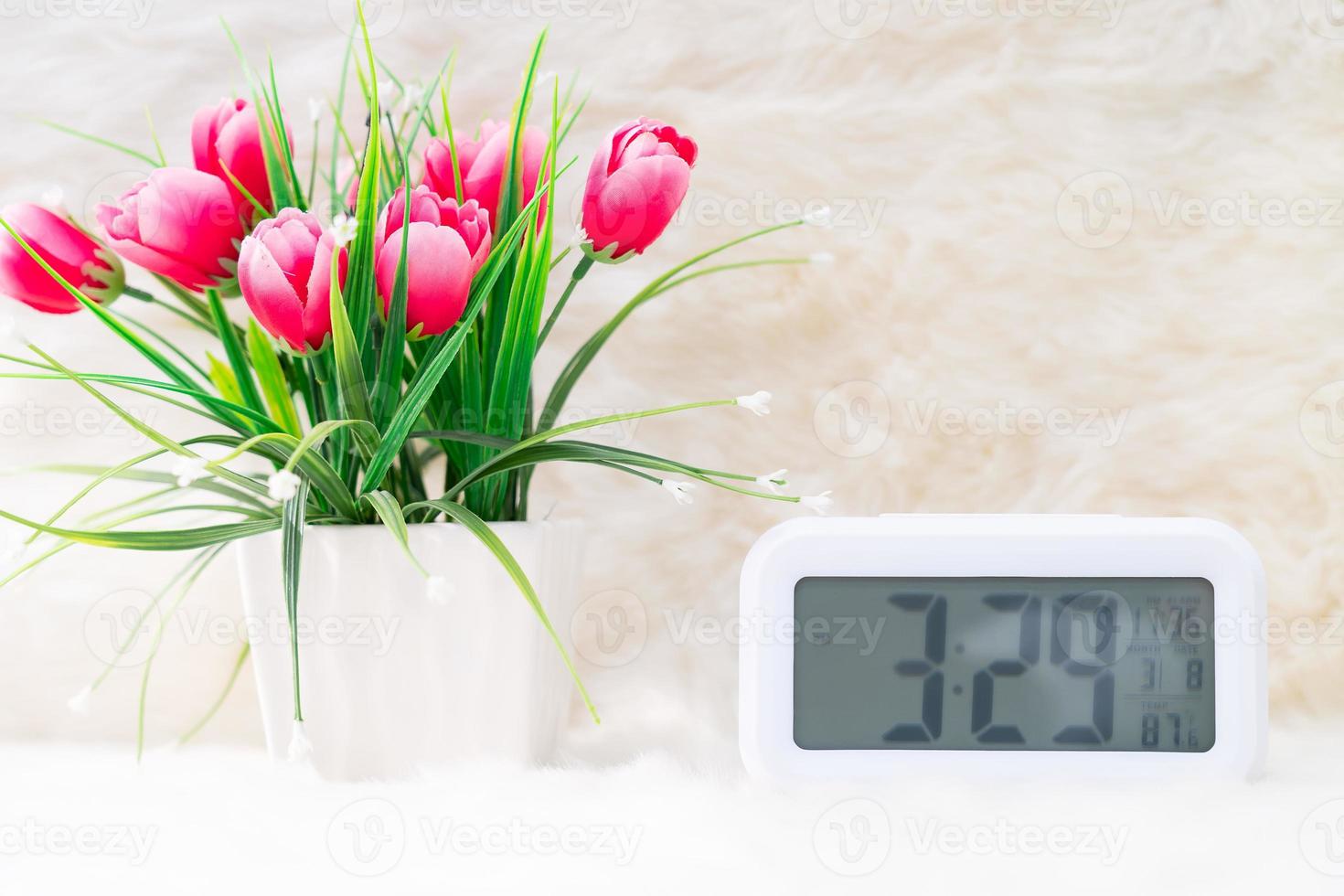 reloj digital con flora decorada en la mesa foto
