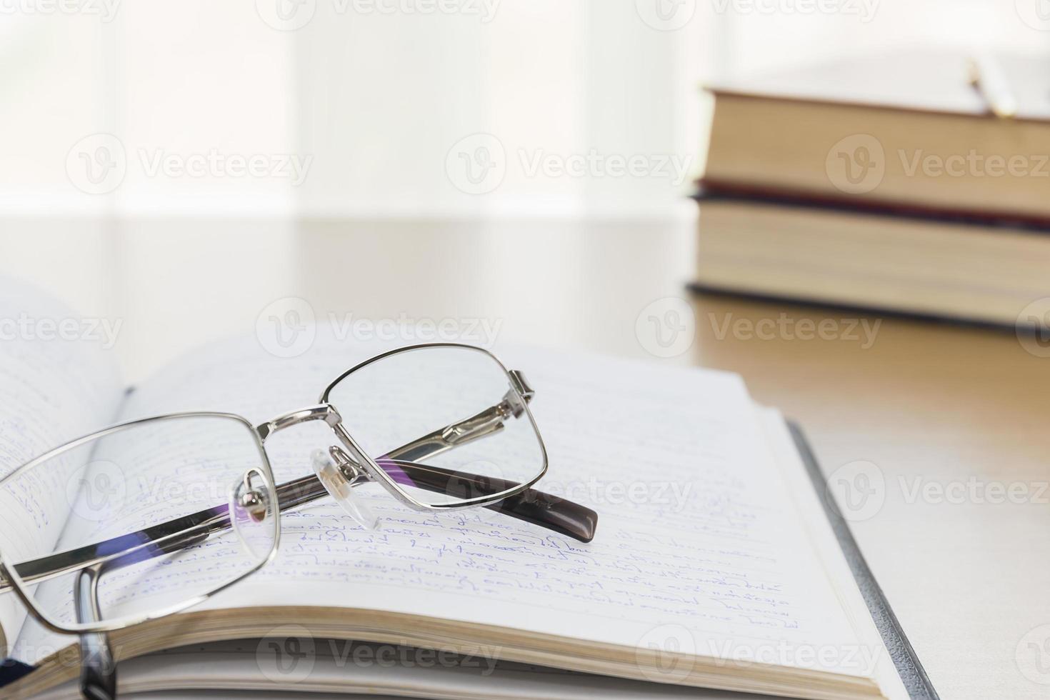 Eyeglasses put on notebook on wood table photo