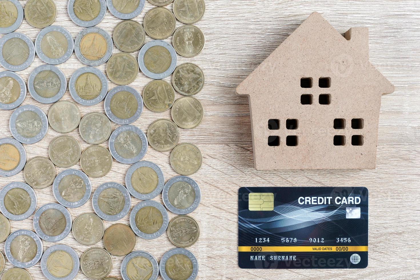 Top view house model and coins with credit card on wood table photo