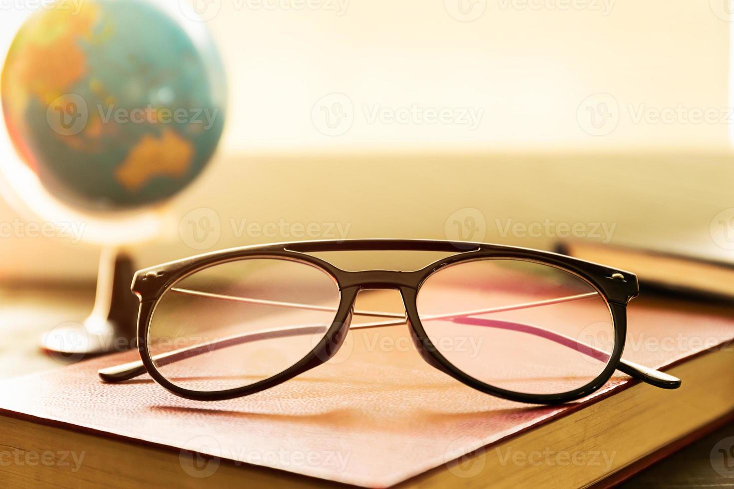 Eye glasses and books beside the window photo